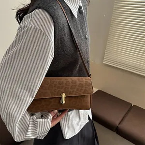 Dettaglio della borsa sottobraccio leopardata con fibbia dorata su un outfit a righe