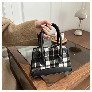 Détail du tissu à carreaux et coutures en cuir sur un sac seau élégant pour femme