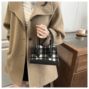 Gros plan d'un mini sac seau à carreaux avec tissu en tweed et poignée en cuir noir