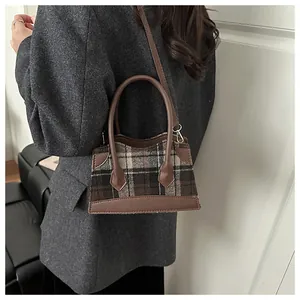 Vue détaillée d'un sac à carreaux vintage porté avec un élégant blazer gris pour femme