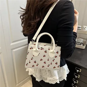 Fashionable white tote bag with cherry prints featuring top handles and long shoulder strap
