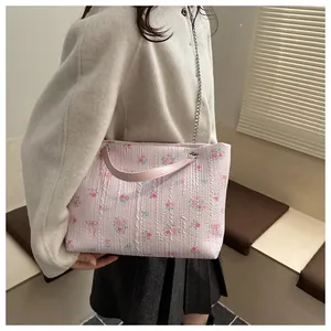 Detail of pink floral shoulder bag with ribbon bow and silver chain on model