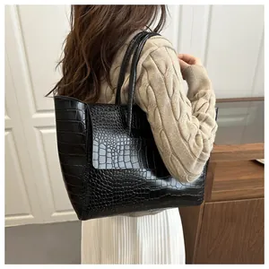 Detail view of large black crocodile pattern tote bag with polished finish and dual straps