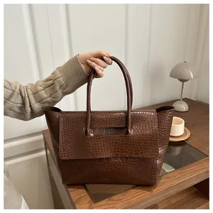 Detailed texture of dark brown faux crocodile leather tote bag with sturdy handles
