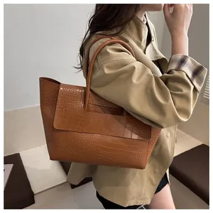 Brown crocodile embossed tote bag shown on model with classic trench coat