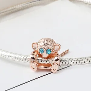 Detalle del dije de mono oro rosa con ojos de cristal azul en pulsera de cadena de serpiente