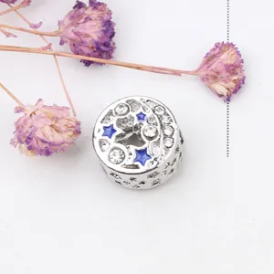 Silver bead charm with blue stars and clear zircons on a white textured background