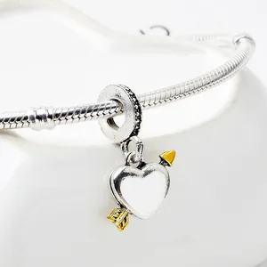 Makro-Detail von silber-goldenem Cupido-Herzanhänger an einem Schlangenarmband