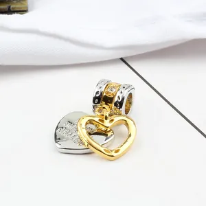 Detail of two-tone gold and silver heart charms with engraved text and crystal bead