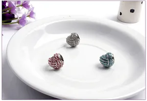 Close-up of heart-shaped DIY charm beads with white, pink, and blue rhinestones on a tray