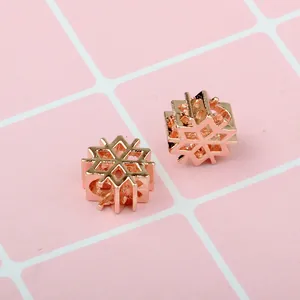 Dettaglio macro di ciondoli a fiocco di neve in oro rosa con motivi geometrici per DIY