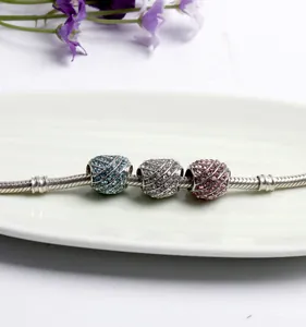 Silver snake chain bracelet with blue and pink pavé heart charms on a white plate