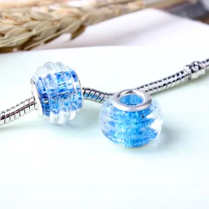 Blue spiral glass charms on a silver snake chain bracelet with natural dry grass decor