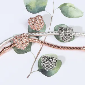 Details van tweekleurige hartbedeltjes met pavé kristallen op een slangenarmband