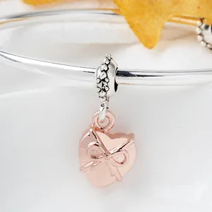 Brazalete de plata pulida con colgante de corazón y lazo en oro rosa sobre blanco