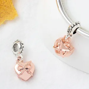 Colgante corazón oro rosa con lazo y eslabón de plata sobre fondo mármol