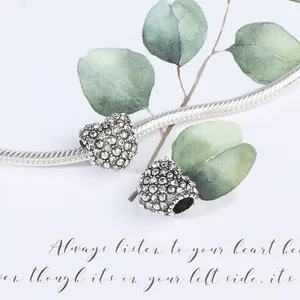 Detailweergave van zilveren slangenkettingarmband met twee hartvormige kristallen bedels