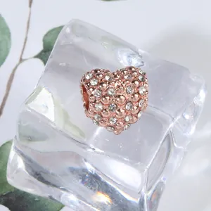 Macrodetail van roségouden hartbedeltje met pavé zirkonia op een helder ijsoppervlak