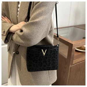 Chic leopard print crossbody bag with gold V hardware styled on a khaki coat