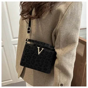 Detail of leopard print crossbody bag with golden V-buckle on a stylish suede texture