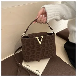 Close-up of leopard print handbag with gold V-buckle and adjustable shoulder strap