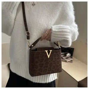 Detail of leopard print handbag featuring a gold V-shaped metal buckle and suede texture