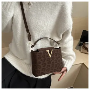 Close-up of leopard print handbag with golden V buckle worn with white sweater