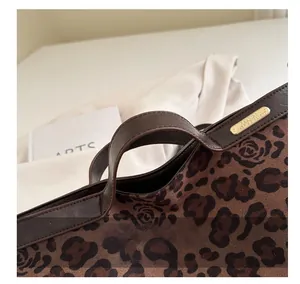 Detail of vintage leopard print handbag featuring a brown leather handle and gold hardware