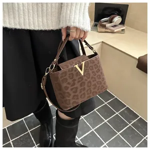 Detail of leopard print crossbody bag with gold V-buckle and textured leather finish