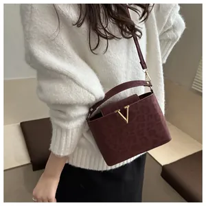 Close-up of burgundy leopard print bucket bag with gold V logo and adjustable strap