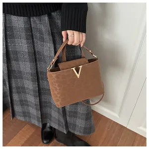 Close-up of leopard pattern handbag with golden V-clasp on crossbody strap