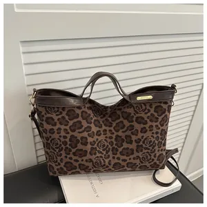 Détail du sac cabas imprimé léopard et rose avec anses en cuir marron sur des livres blancs