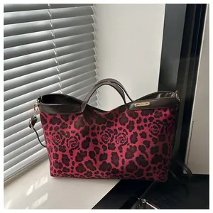 Détail du sac cabas léopard rouge et floral avec bordure en similicuir brun et logo doré