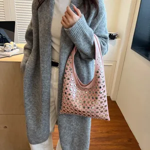 Détail du sac à bandoulière rose clair avec rivets argentés porté par un mannequin en tenue