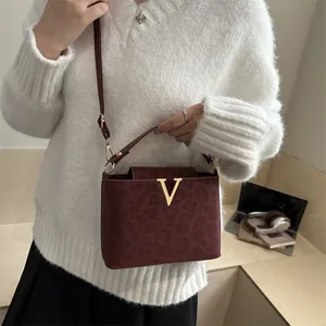 Fashionable burgundy leopard print crossbody bag with gold V buckle and top handle
