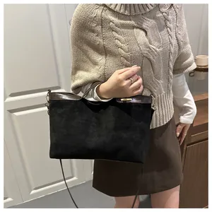 Détail du cabas en daim noir et cuir marron montrant les coutures et la plaque en métal