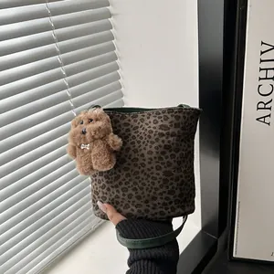 Leopard print bucket bag with dark green trim and a cute plush bear charm held by hand