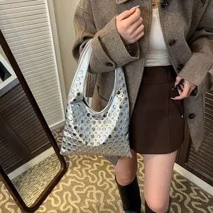 Sac hobo argenté avec rivets métalliques et forme de croissant porté à l'épaule