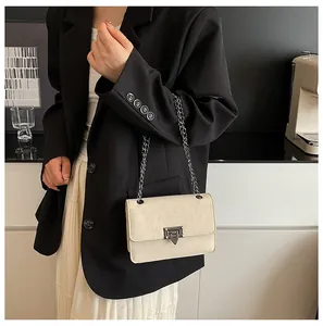 Detail of minimalist cream PU leather crossbody bag with silver metal buckle and chain