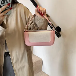 Detail of a pink and cream patchwork baguette bag with adjustable strap on a model