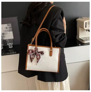 Détail du sac à main blanc gaufré avec poignées marron et ruban à motif de cœur