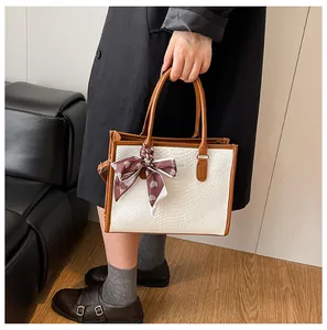 Détail d'un sac cabas blanc à motif crocodile avec anses brunes et foulard à coeurs