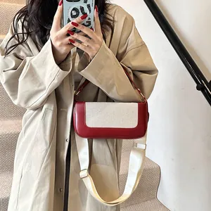 Detail of vintage red and beige patchwork leather bag with textured canvas and wide strap