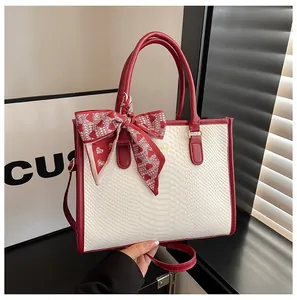 Détail de la texture serpent sur sac à main en cuir avec bordure rouge et foulard