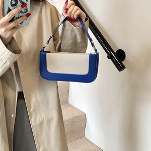 Mirror selfie showing a color-blocked blue and beige small square crossbody bag