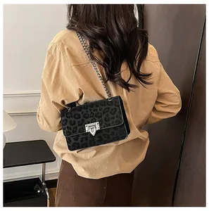 Detailed view of leopard print square chain bag worn over the shoulder by a model