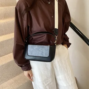 Detail of a minimalist two-tone crossbody bag with wide white strap on a model