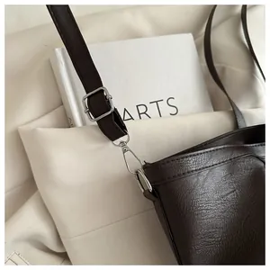 Detail of dark brown leather shoulder bag with silver buckle and adjustable metal strap