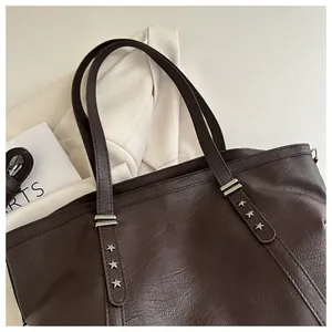 Detail of dark brown tote bag featuring silver star rivets and premium pebbled leather texture