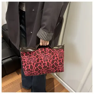 Gros plan du sac cabas rouge à motif léopard avec bordure en cuir et logo métallique